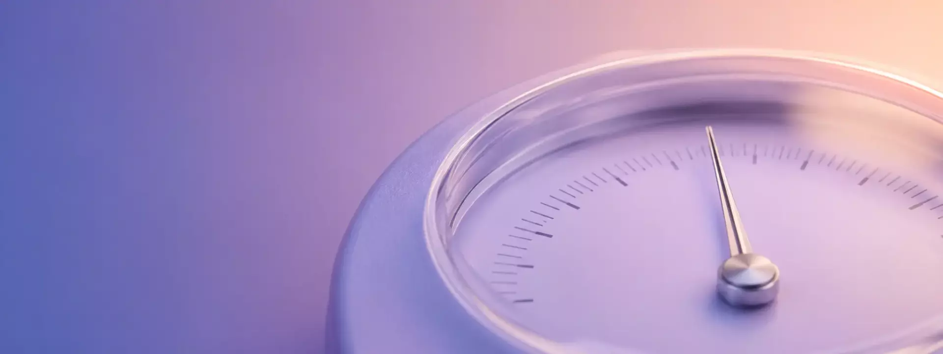 Close-up of a circular analog gauge with a silver needle and measurement marks, set against a purple–peach gradient background