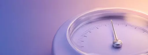 Close-up of a circular analog gauge with a silver needle and measurement marks, set against a purple–peach gradient background