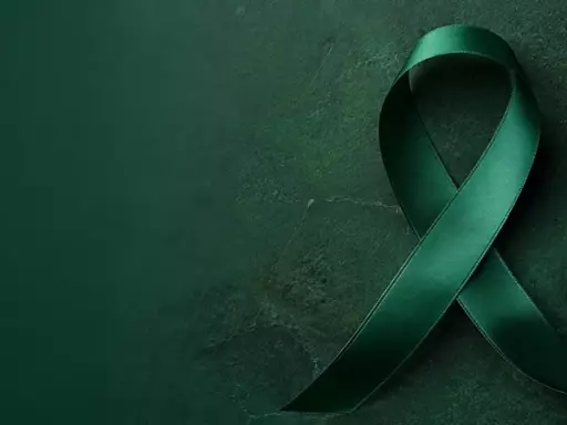 Green awareness ribbon on a dark green textured background.
