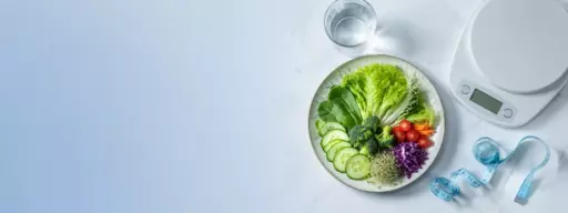 Plate of fresh vegetables with a kitchen scale and a measuring tape on a light marble surface.