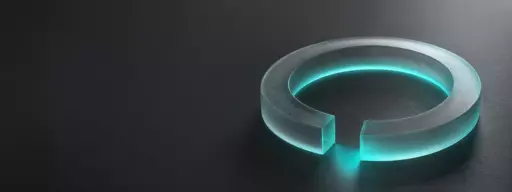 Teal-glowing circular ring with a gap, resting on a dark surface.