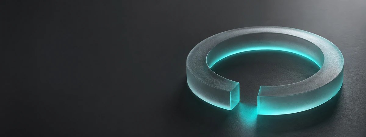 Teal-glowing circular ring with a gap, resting on a dark surface.